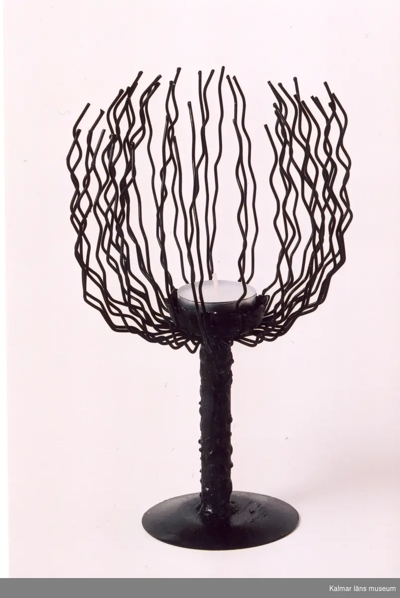 KLM 39586:35 Ljusstake i form av stiliserat träd av metall och ståltråd, svartmålad. Tillverkad i konstsmide/trådarbete, svetsad. Tillverkad av trådslöjdare Yngve Axtelius.