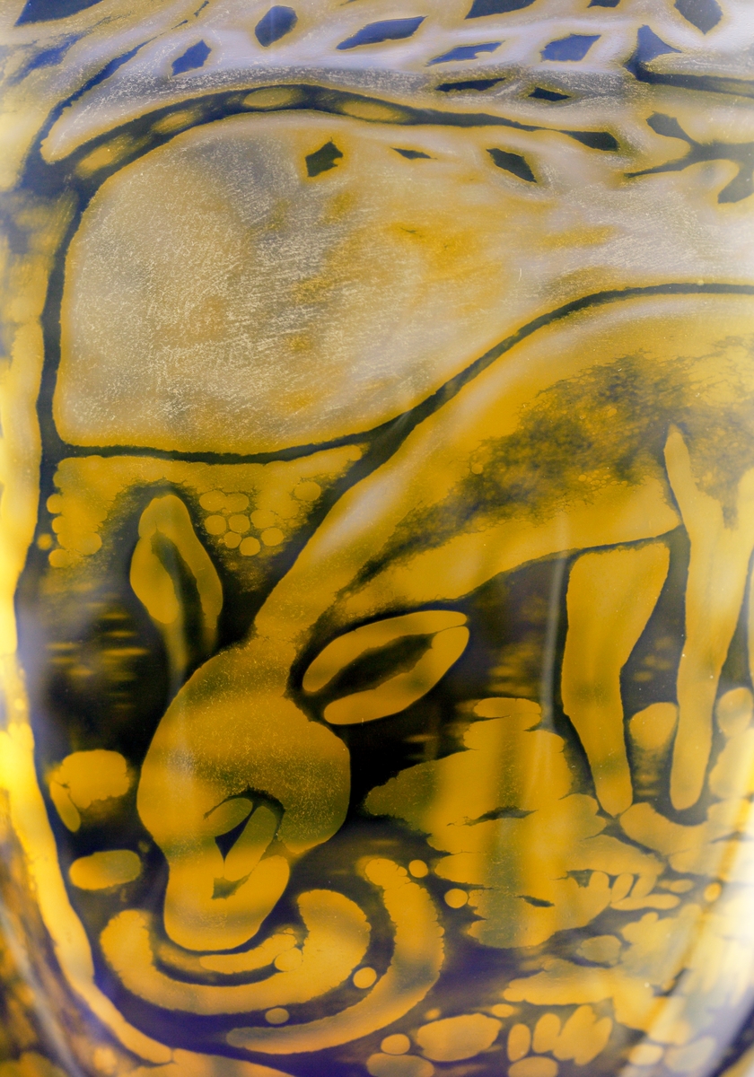 Graalskål av Eva Englund med växt- och djurmotiv i transparant blått och gult.
