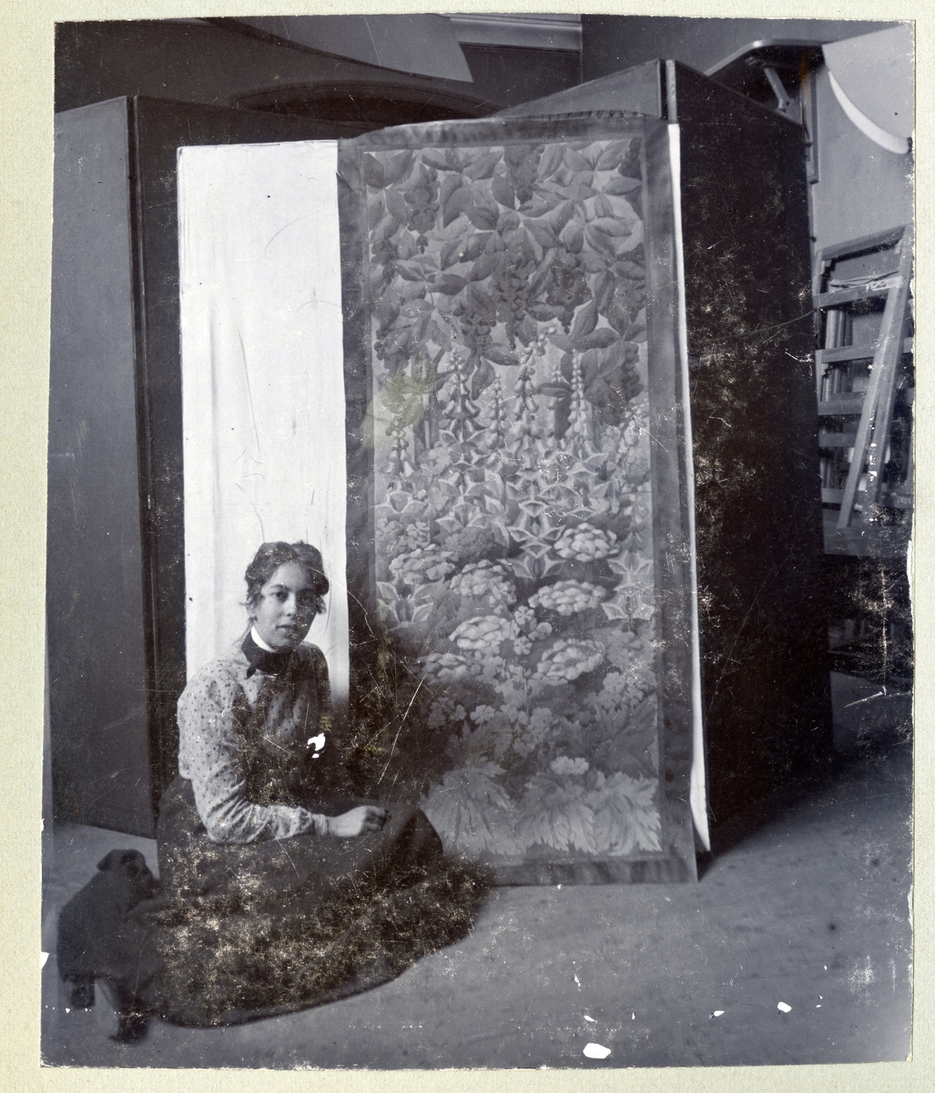 Stockholm. 
Kvinna sittande på golvet framför målning. 1901.
