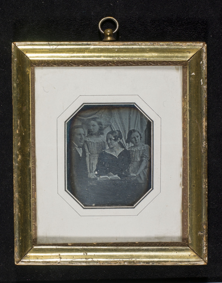 Daguerreotypi av ektepar sammen med to døtre, samlet ved et bord.