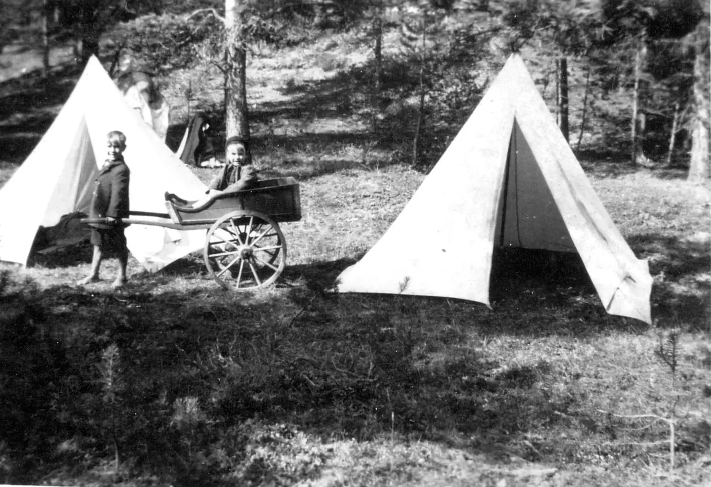 Barn i lek med håndkjerre foran knappetelt.