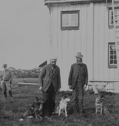 Bildet viser tre menn og tre hunder foran et hus i Svankild,