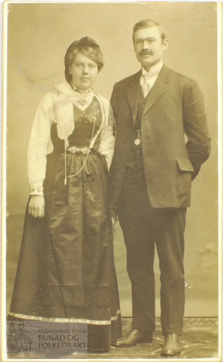 Fotografi av ektepar. Kvinna i bunad med tulleplagg og mannen i dress.
På bakside står "Nr 3 Lofthus Dalen"
Fotograf: Th. Finne, Carl Johansgade 19, Kristiania, eneret.
