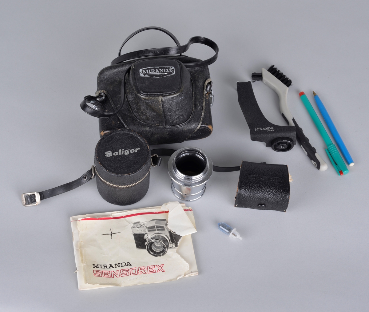 Analogt fotoapparat av typen Miranda Sensorex. 
Plassert i fotbag med tilleggsutstyr: ekstra linse og objektiv, bruksanvisning, børste for renhold, blitslampe og skrivemateriell.