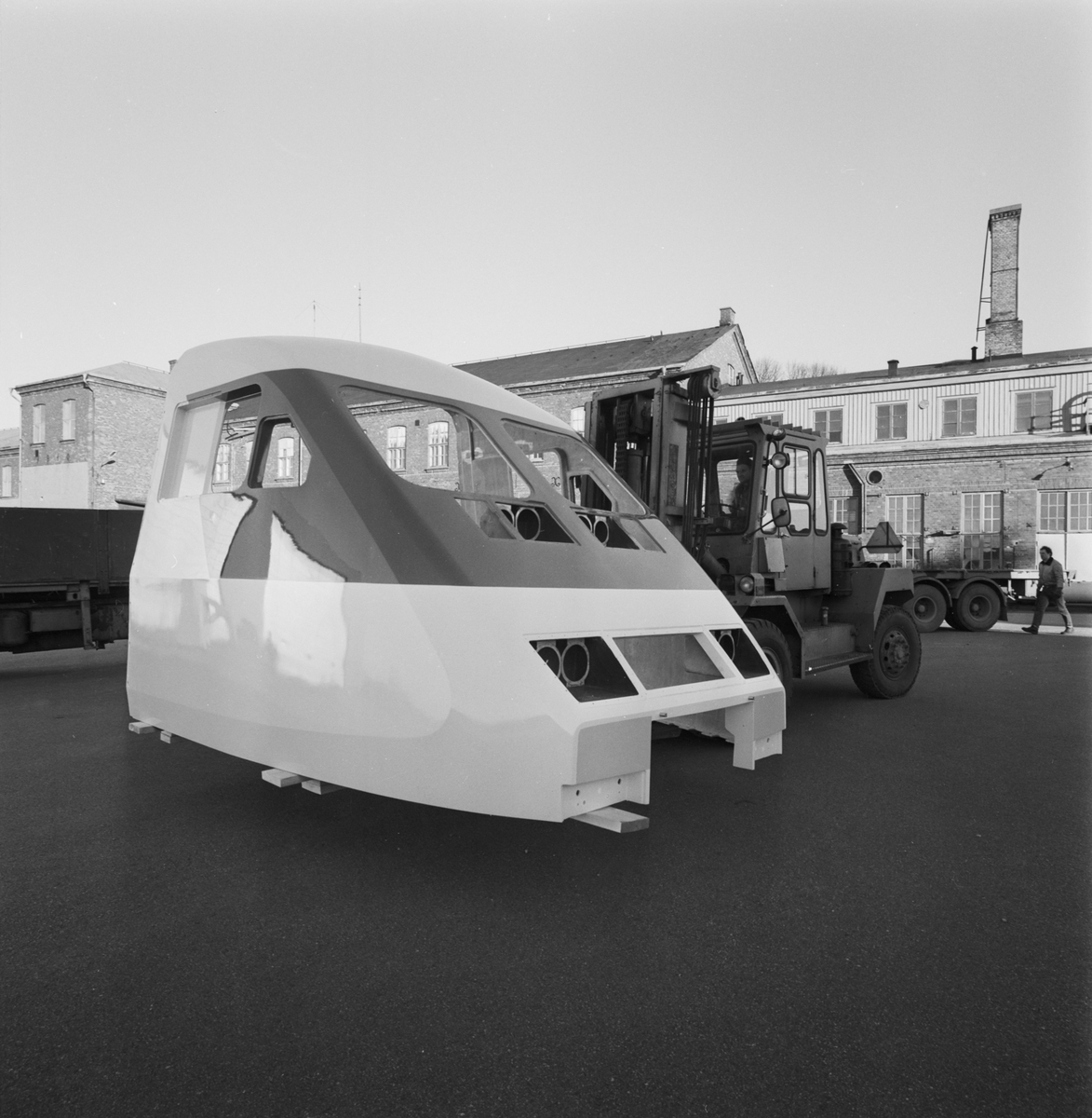 En gaffeltruck lyfter upp en förarhytt för en X 2000 tåg som ska lastas på en lastbil.