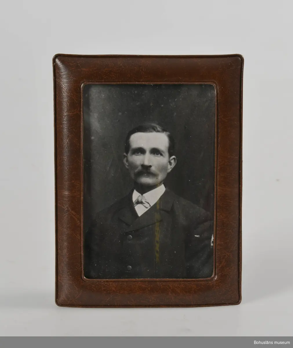 Svarvitt fotografi i ram av brun plast.
På baksidan antecknat med bläck:
Morfar Johannes Jonson Löndal.