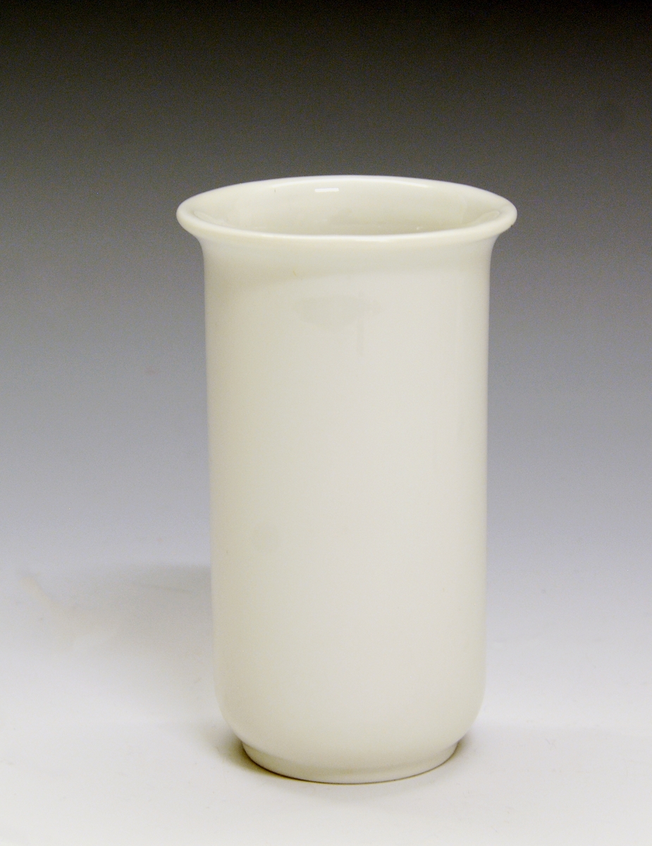 Prot: Liten vase av porselen. Sylinder med innrykket, lav fotrand og liten utbrettet kant. Hvit glasur uten dekor. 
Modell: 2113 "Cylinder"