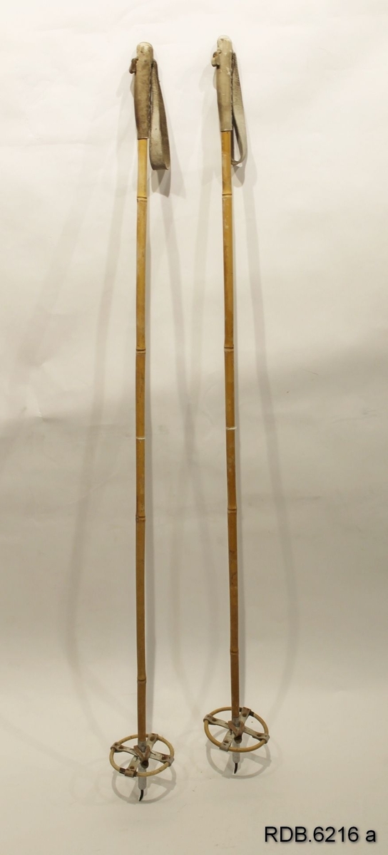 Et par skistaver av bambus med opprinnelig kvite, sydde lærhåndtak med regulerbare handreimer. Bambustrinser (kringler) med fastnaglede lærkryss som er naglet fast til staven. Aluminiumsholker med bøyde jernpigger.