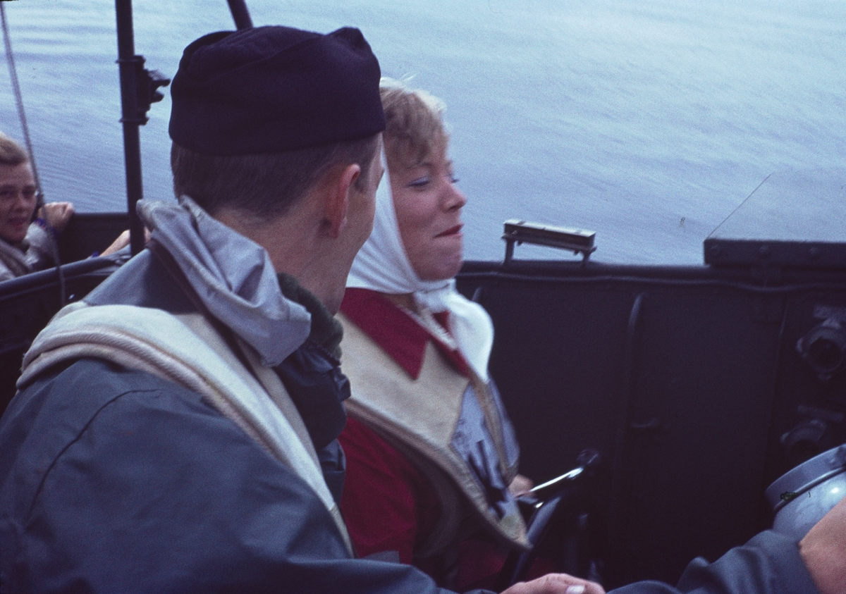 Bilden visar en besättningsmän och en kvinnlig besökare i skyddskläder ombord på en motortorpedbåt.