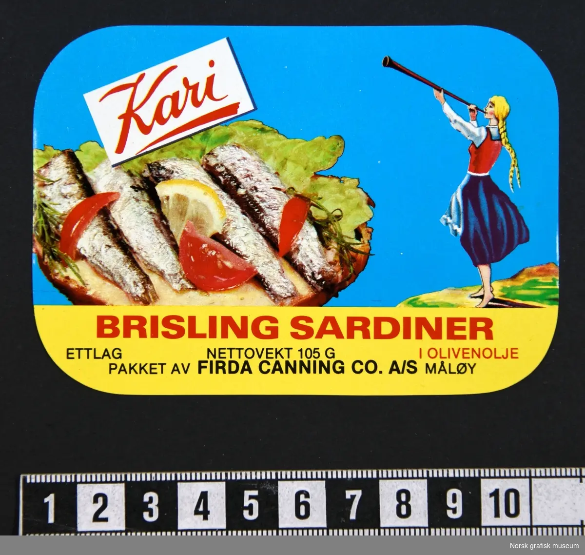 Etikett med blå bakgrunnsfarge, en illustrasjon av en kvinne med blonde fletter som blåser i en lur på høyre side, og sardiner dandert (på en brødskive?) med grønnsaker og sitron på venstre side av etiketten. 

"Brisling sardiner i olivenolje"