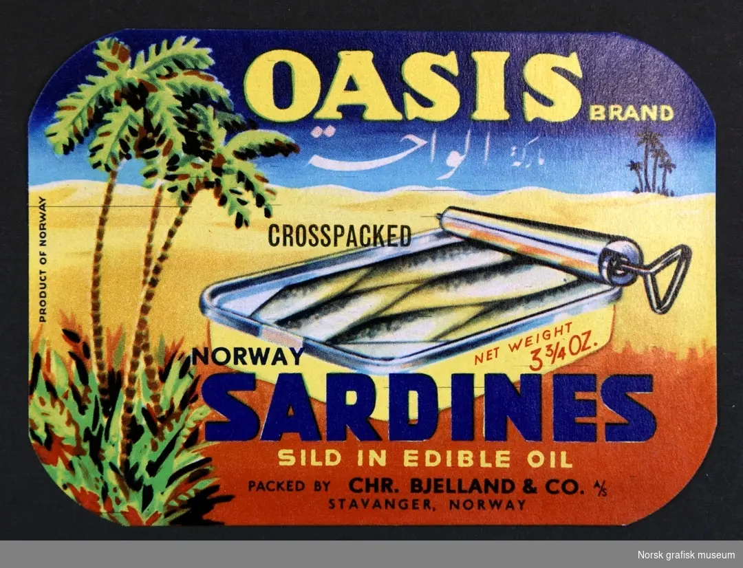 Etikett med en fremstilling av en åpnet hermetikkboks i et landskap av sand og palmer. 

"Norway sardines sild in edible oil"