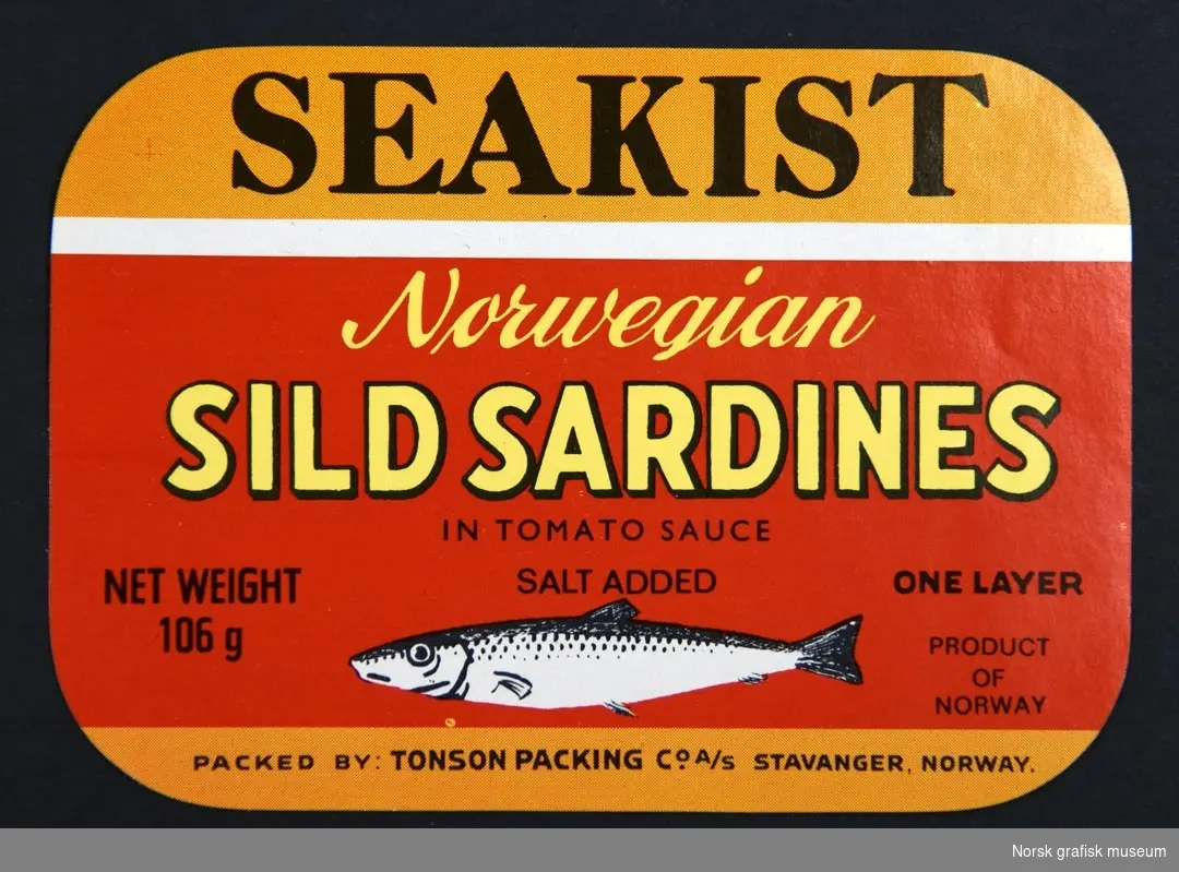 Etikett i rødt og oransje, med detaljer i gult, sort og hvitt. Nederst er en illustrasjon av en fisk. 

"Norwegian sild sardines in tomato sauce"