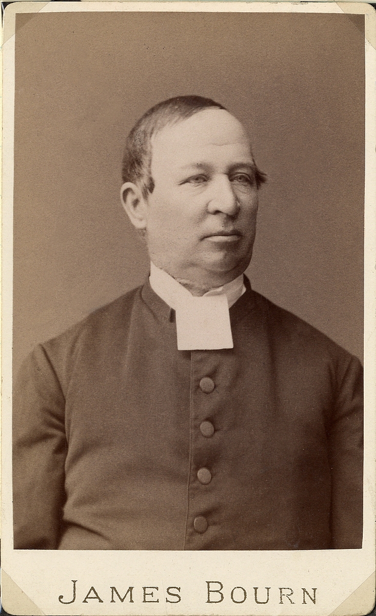 Foto av en man i prästrock med stärkkrage och prästkrage.
Bröstbild, halvprofil. Ateljéfoto.