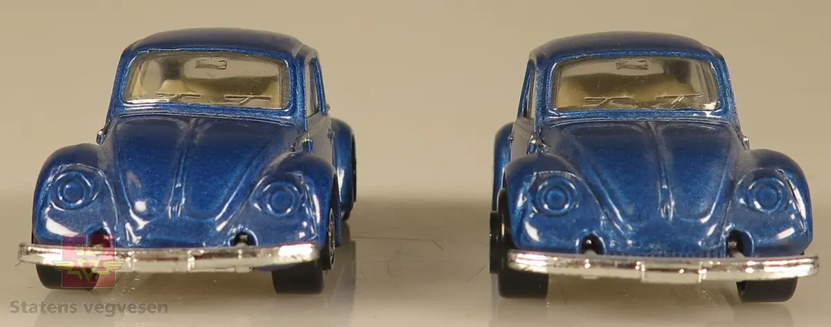 Samling av flere modellbiler.  De to bilene er blå med hvitt interiør. Begge er laget av metall og har en skala på 1:64.