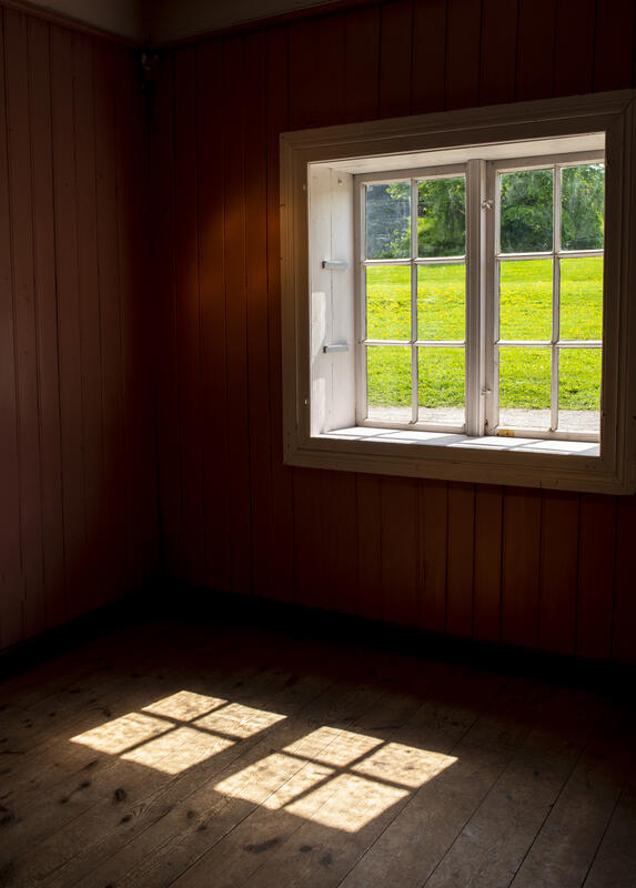 Smårutete vindusglass slipper sollyset inn slik at det dannes flotte skygger på tregolvet i Løtenbygningen.