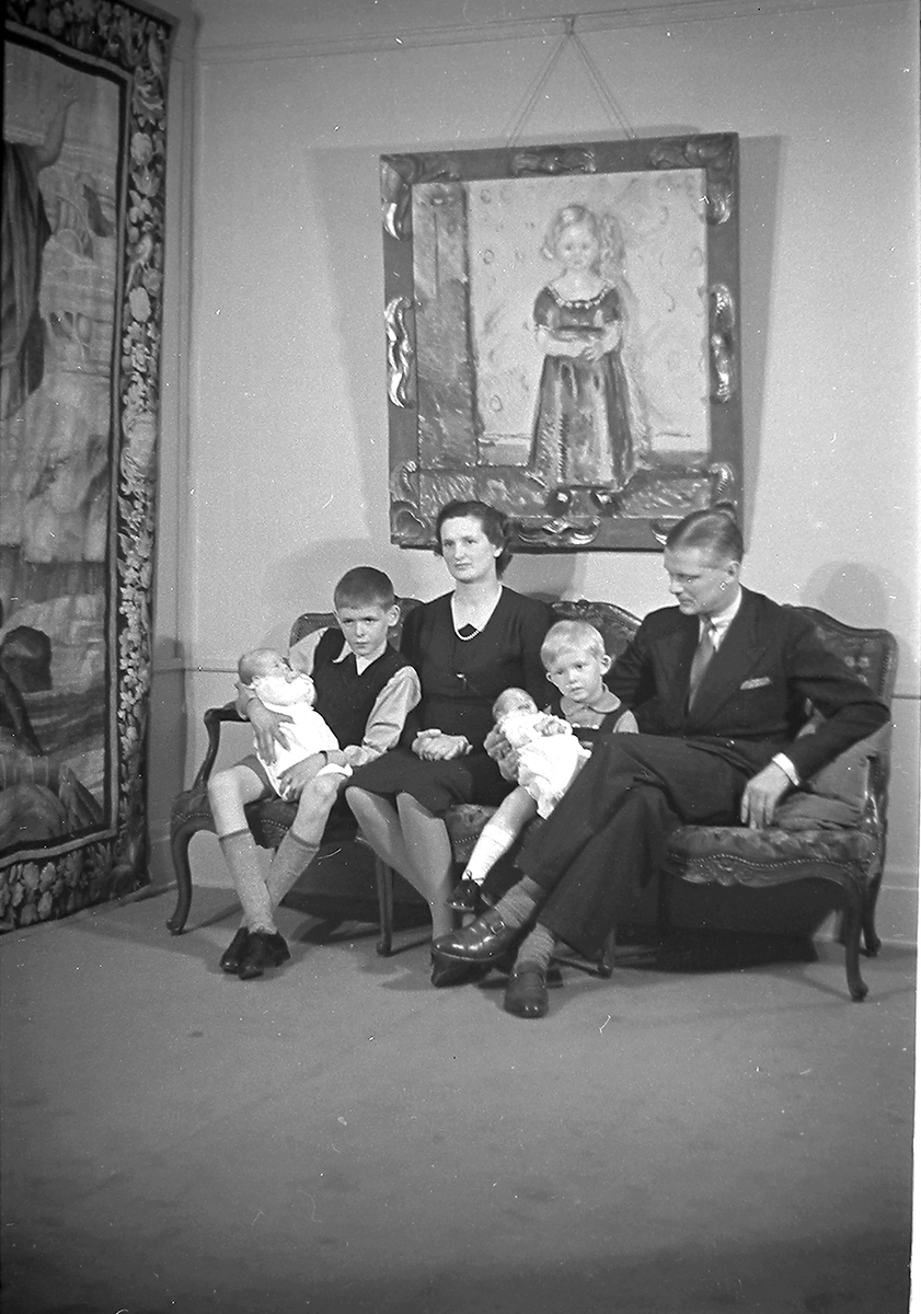 Familien Astrup sitter med to gutter og tvillinger i sofa. Fotografert 1939.