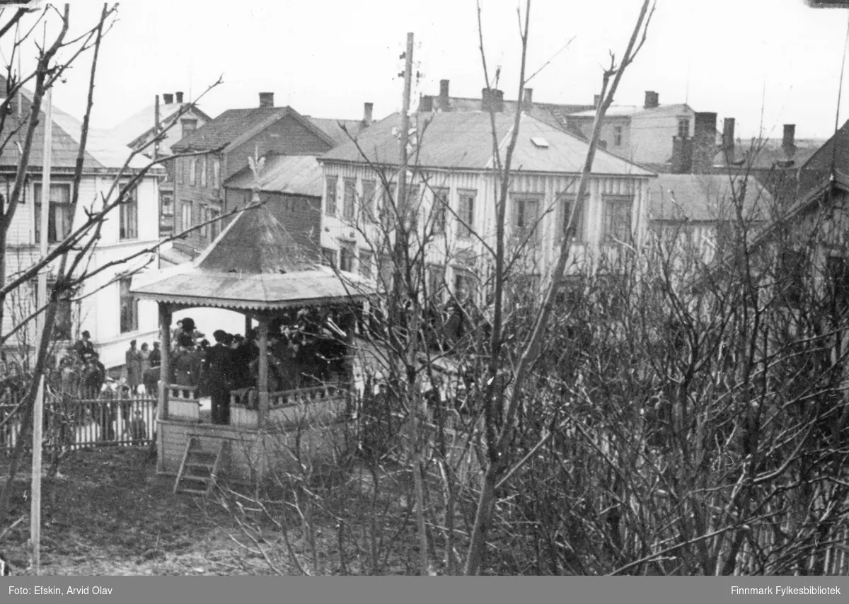 Musikktime i paviljongen i Vadsø, 1939. Huset til venstre er Vinjevold gården og huset til høyre er Henriksens bakeri. Fra rundt samme sted finnes bilder FBib.98012-226 og FBib.01009-093.

