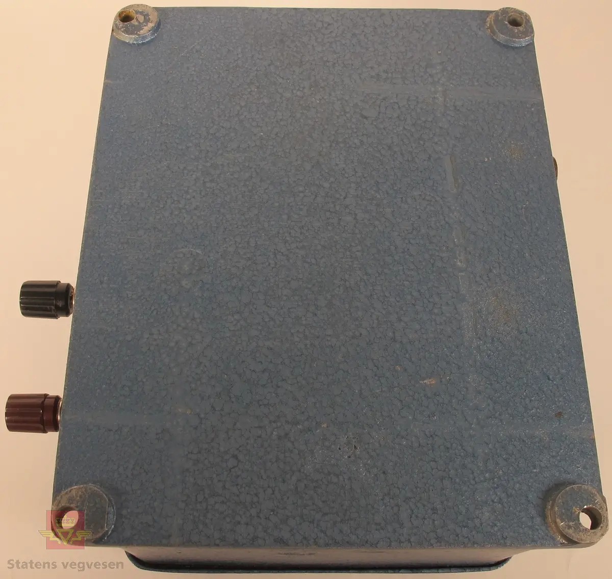 Detektor til lynvarsler i støpt aluminium, lakkert i blått. Detektoren har innskriftene WIDERÖE & BULL A/S INGENIØRFIRMA OSLO D Nr. 35 og TRIPPEL LYNVARSLER på metallplater. Boksen har fire tilkoblingspunkter for kabler, og fire hull for vertikal opphengning.