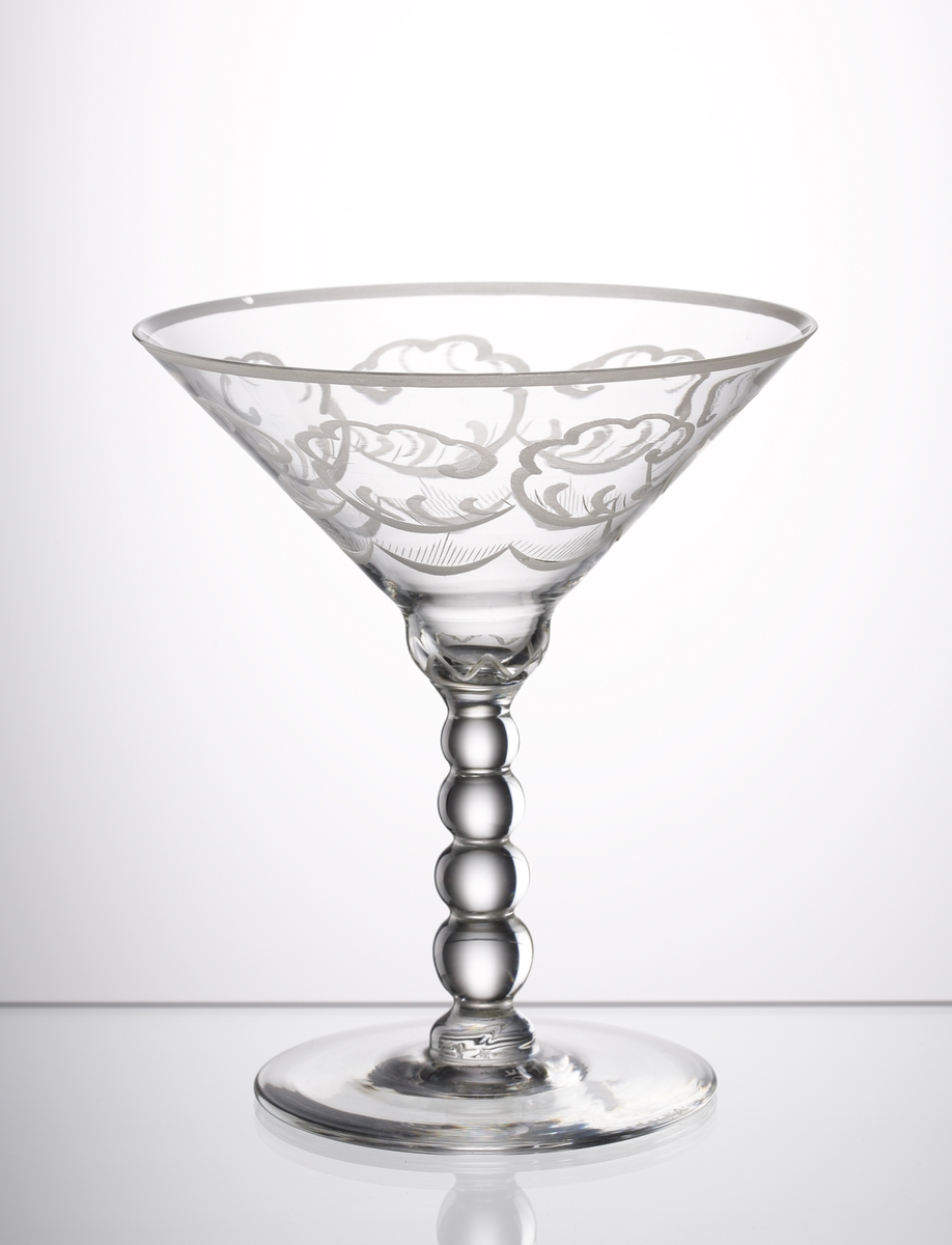"Molnet", av Simon Gate. Cocktailglas på ben och fot. Graverat motiv av moln. Ben med 4 kulor.
