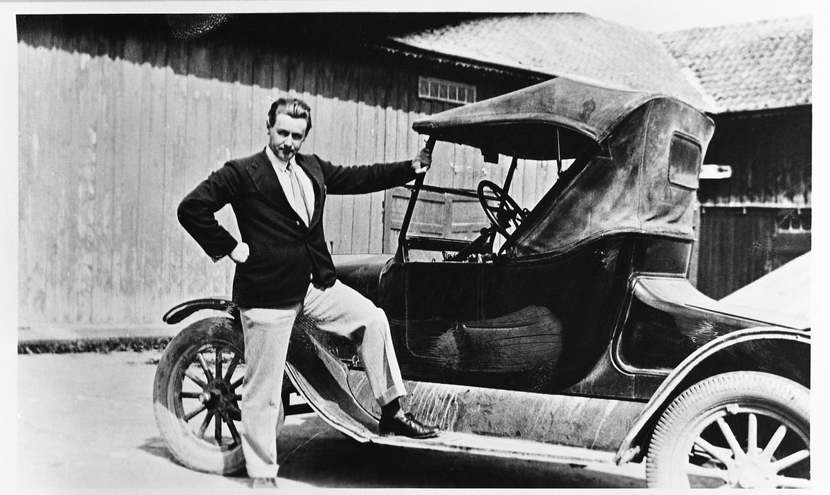 Dyrlege Sverre T. Wang med sin bil foran et uthus med steintak. Bilen er en Ford fra ca. 1925.