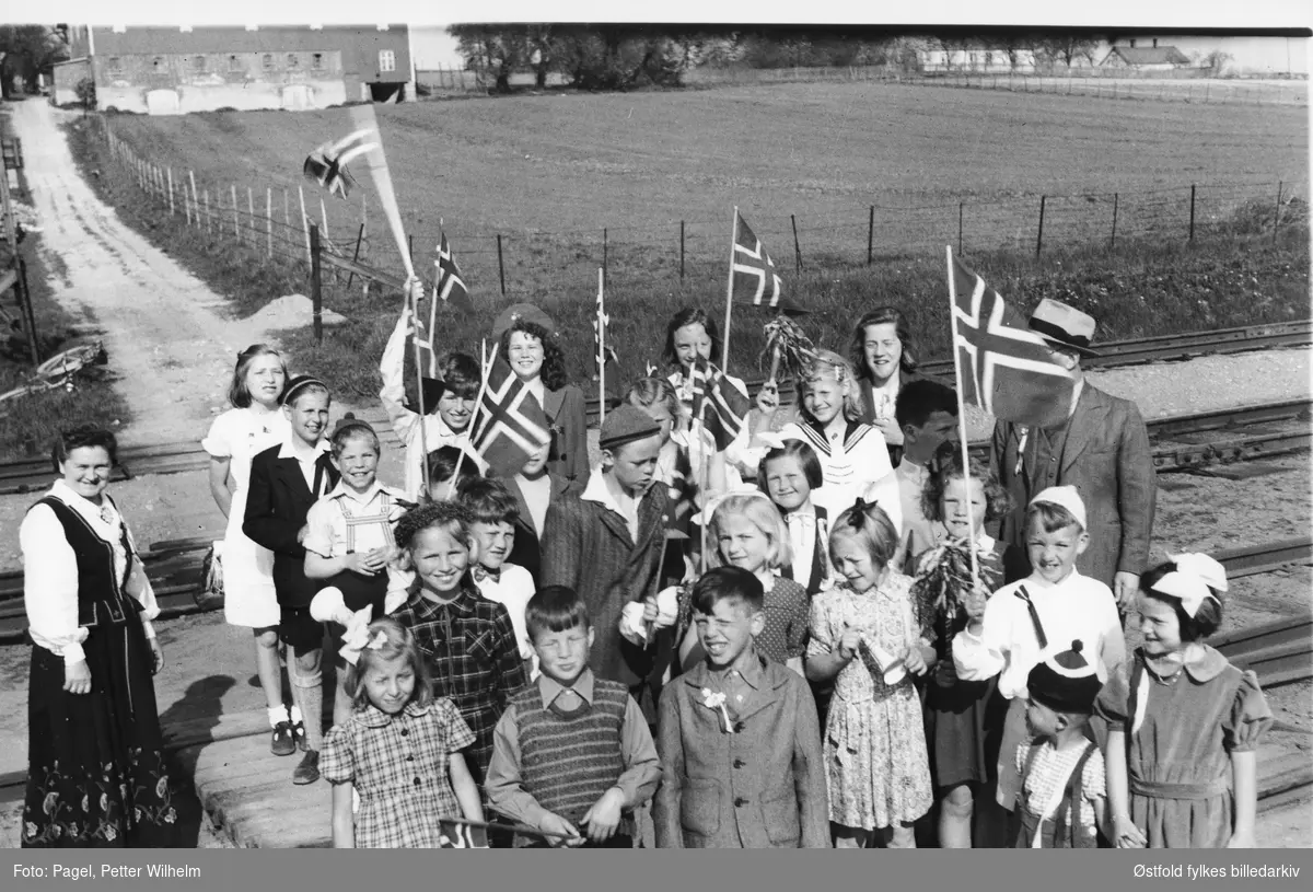 17. mai feiring 1947 for Alvim skole, Brevik jernbaneovergang i Tune. Lite tog med skolebarn fra Alvim skole. Til høyre lærer Molland (bak flagg), til venstre fru Molland. Navneliste - snu arket