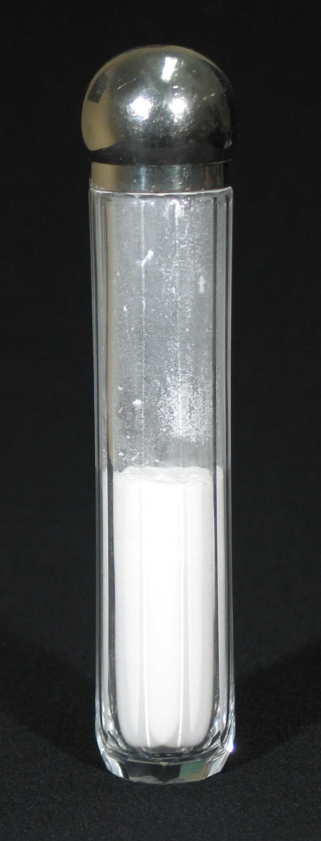 Sylindrisk glassbeholder med sølvfarget kork. Den har slipte kanter og inneholder talkum.