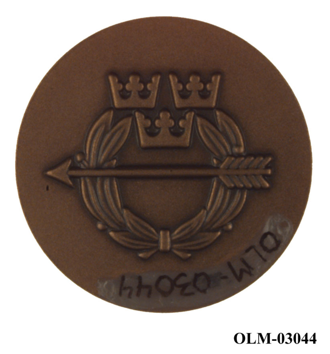 Bronsefarget medalje med motiv av et hode til en ukjent person. Hodet er i profil. Det er også motiv av det som antas å være emblemet til den Frivilliga skytterörelsen.