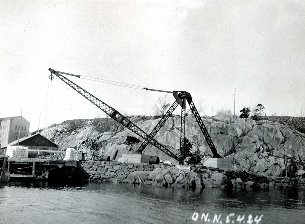"05/04-1924" Nitriden. Montasje av kran på østre kai. Omformerstasjonen sees til venstre, og foran kaianlegget. Tromøysund i forgrunnen.
