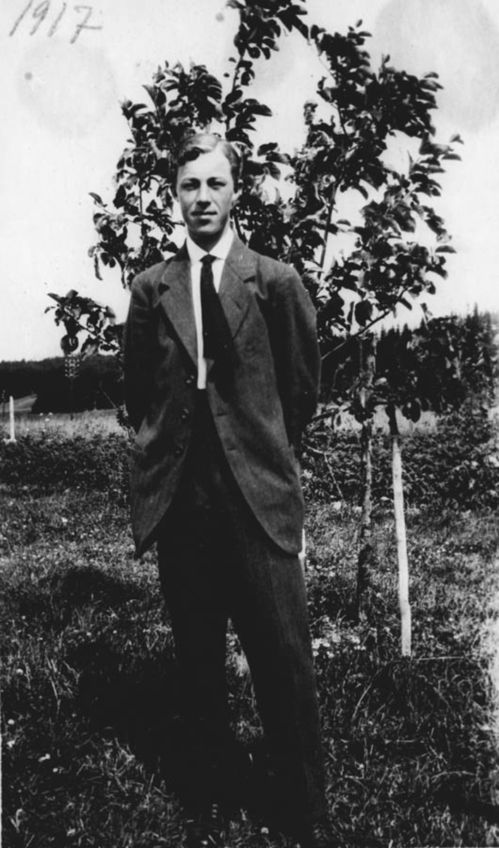 En mann foran et tre i en hage.