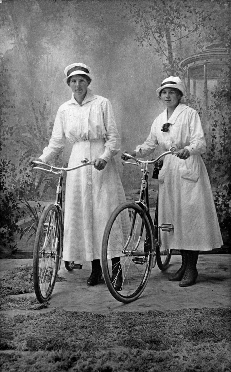 To unge damer med sykler. Atelierbilde.