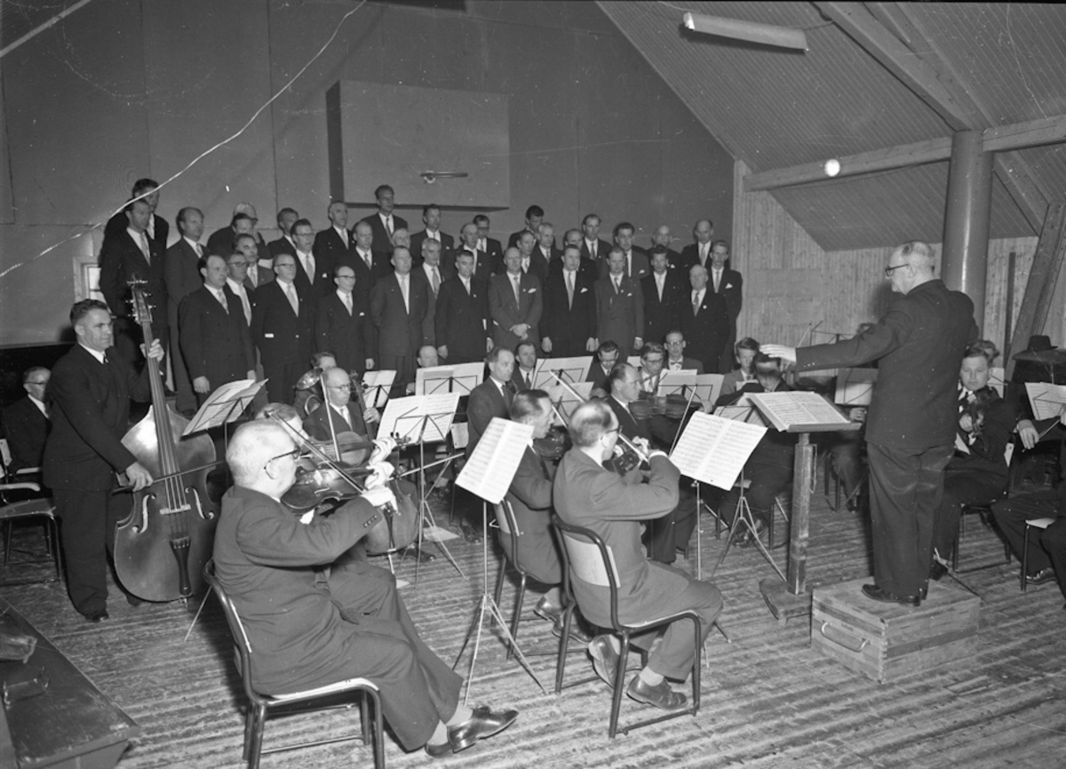 Eidsvoll mannskor(?) og et orkester. Alf Røvang, Odd Otterlei, Svein Underdal og Vidar Engen på bildet.