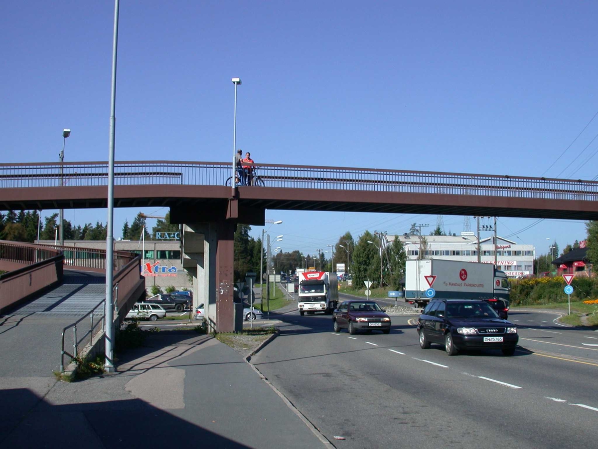 Bil  under gang- og sykkelbroen i Solheimskrysset. To personer på broen.
Fotovinkel: V