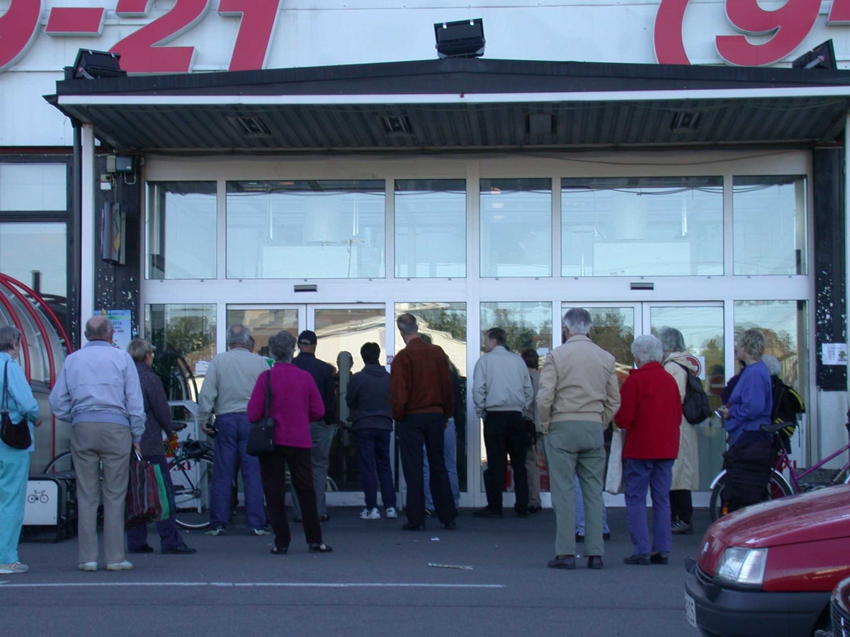 Kundene samles utenfor Maxi kort før butikken åpner om morgenen..
Fotovinkel: S