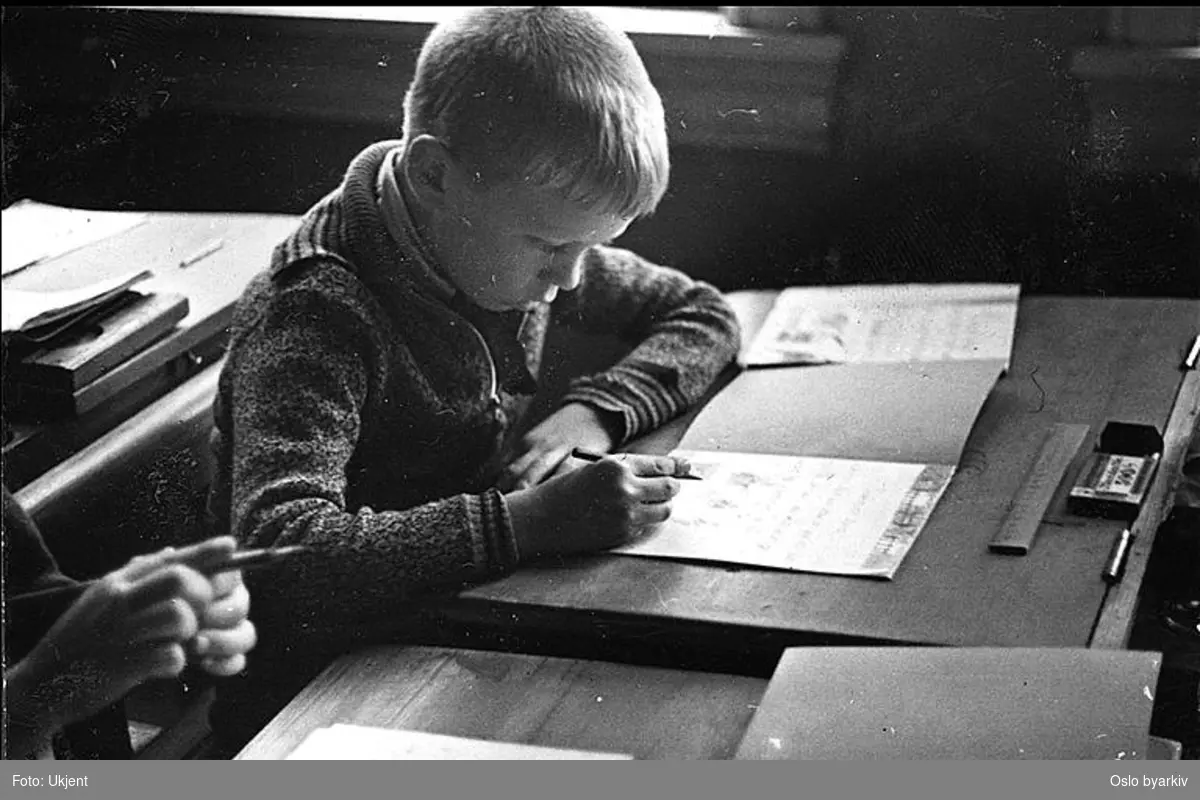 Gutt i dyp konsentrasjon over mattematikkoppgave. Albumtittel: "Sofienberg skole femti år - første september 1933."