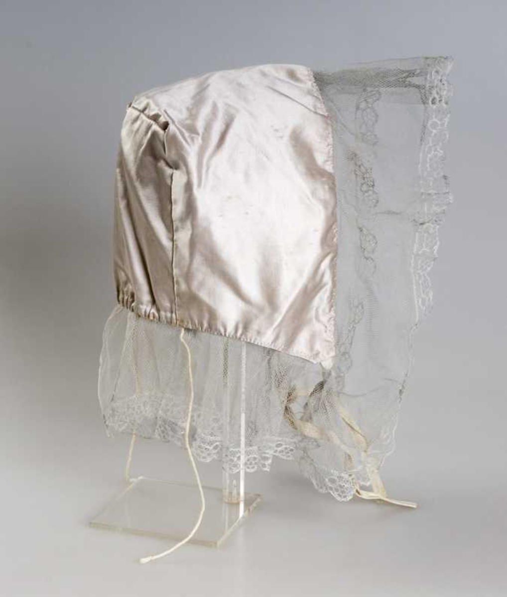 Pullue med firkantet pull, i lys lilla silke, tyllblonde i hvitt bomull. 