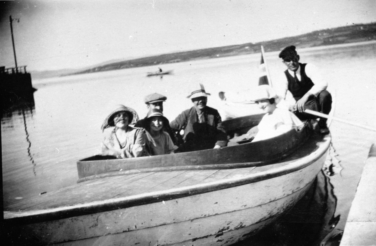 Motorbåt med 5 passasjerer og båtfører Nils Sørbo (1888-1970) ved brygga på Menghoel, Nes, Hedmark.
