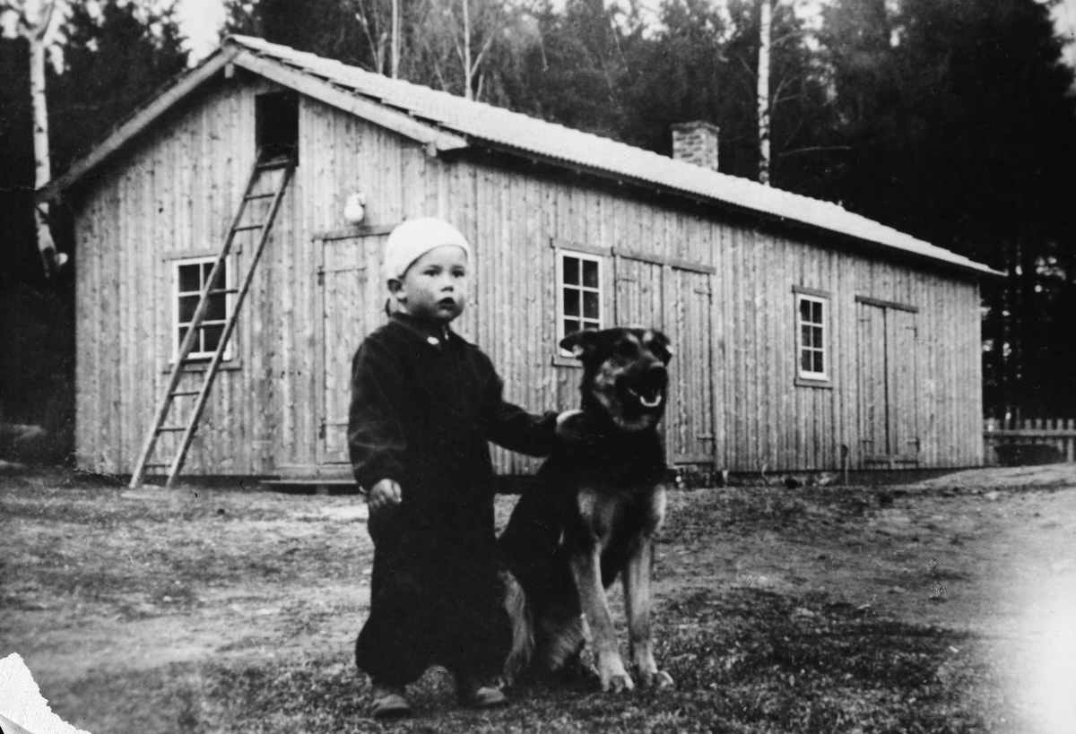Harby & Sandberg, Brumunddal. Det første "fabrikklokalet" Ukjent gutt/hund i forgrunnen. 