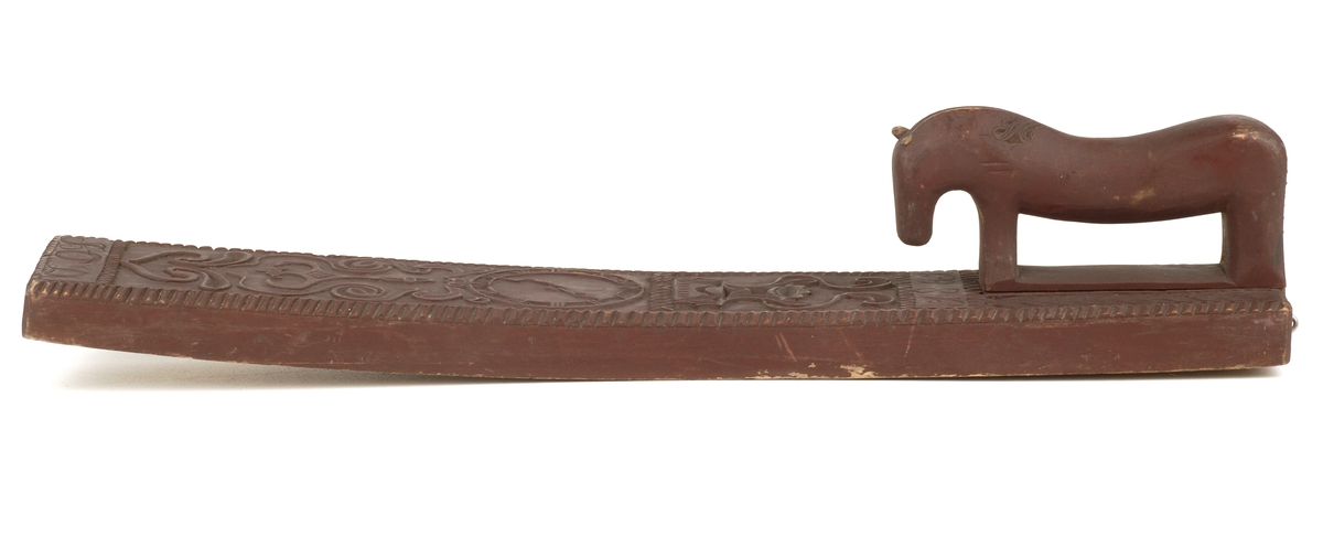 Mangletreets håndtak er utformet som en utskåret hest , med skåren dekor . 
Håndtaksidens overside på mangletreet har til dekor.
Utskårete rankemotiver .