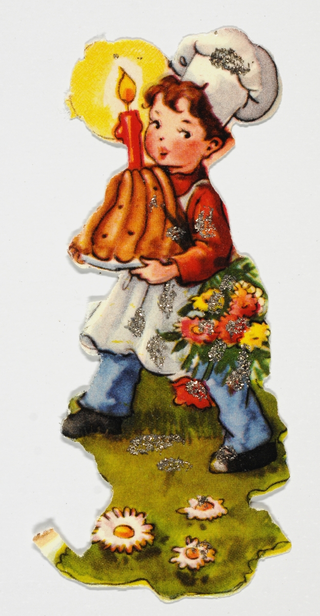 En gutt med kokkelue og forkle kommer bærende med en kake med et tent lys. Blomster i forgrunnen.