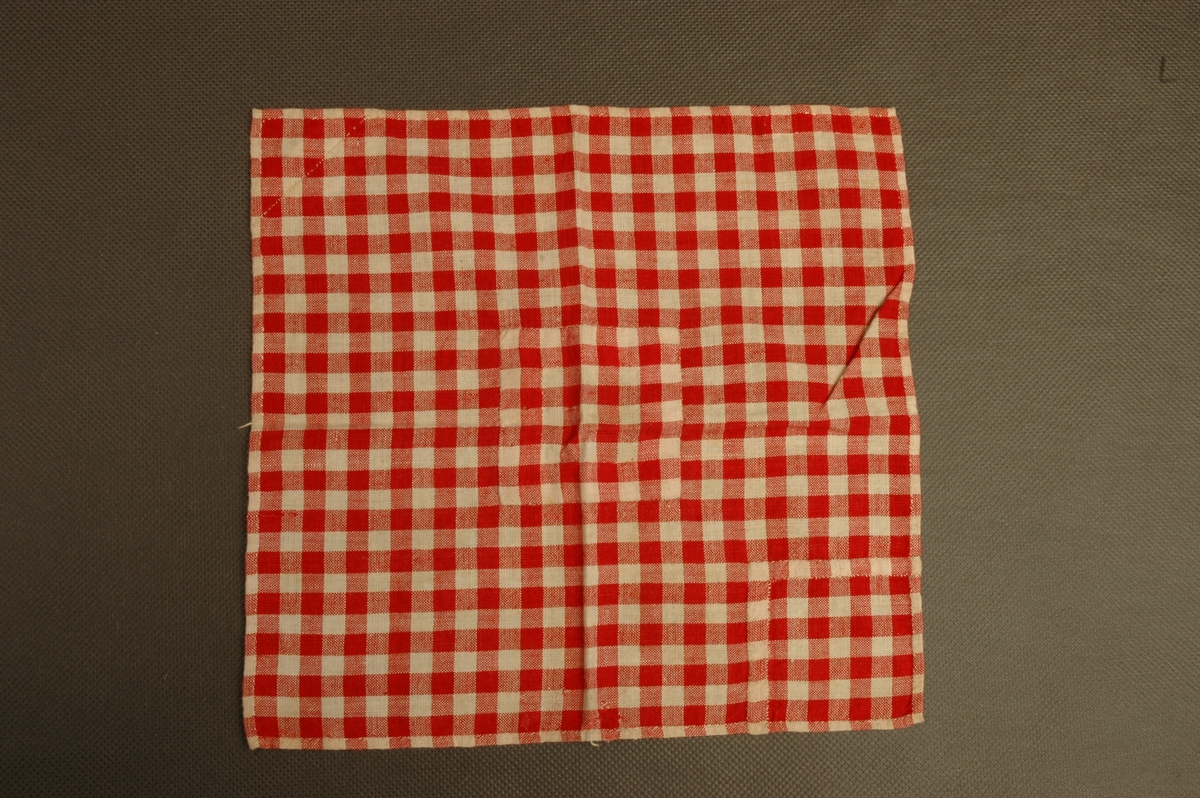 Sømprøve i smårutete stoff med eksempler på to ulike lappinger av hjørner, samt eksempel på lapping av hull midt på lappen.