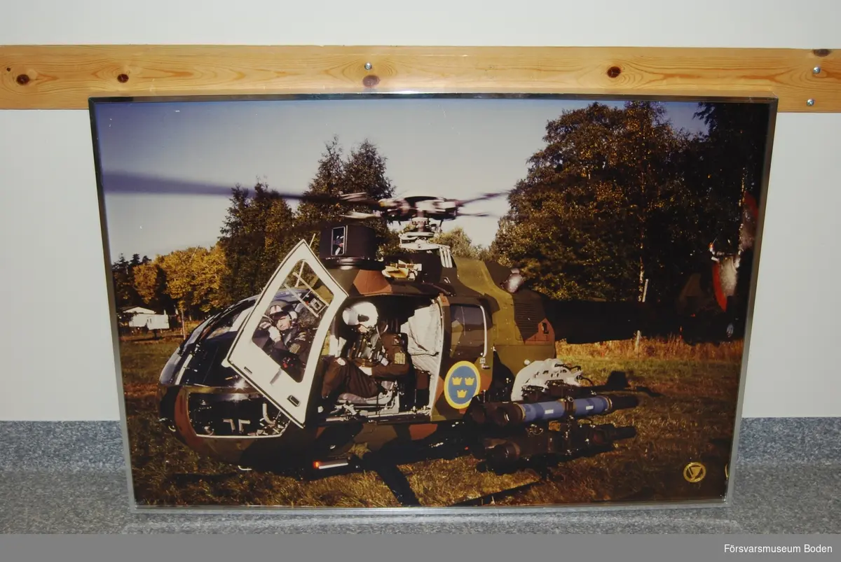 Fotografi med aluminiumram 100,5 x 71 cm. Wire för upphängning på baksidan. Arméflygets truppslagstecken (mössmärke) m/1982 fäst i nedre högra hörnet.