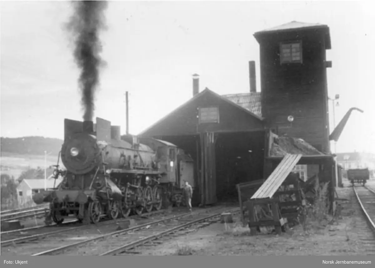 Tynset lokomotivstall med et damplokomotiv av type 26a foran stallen