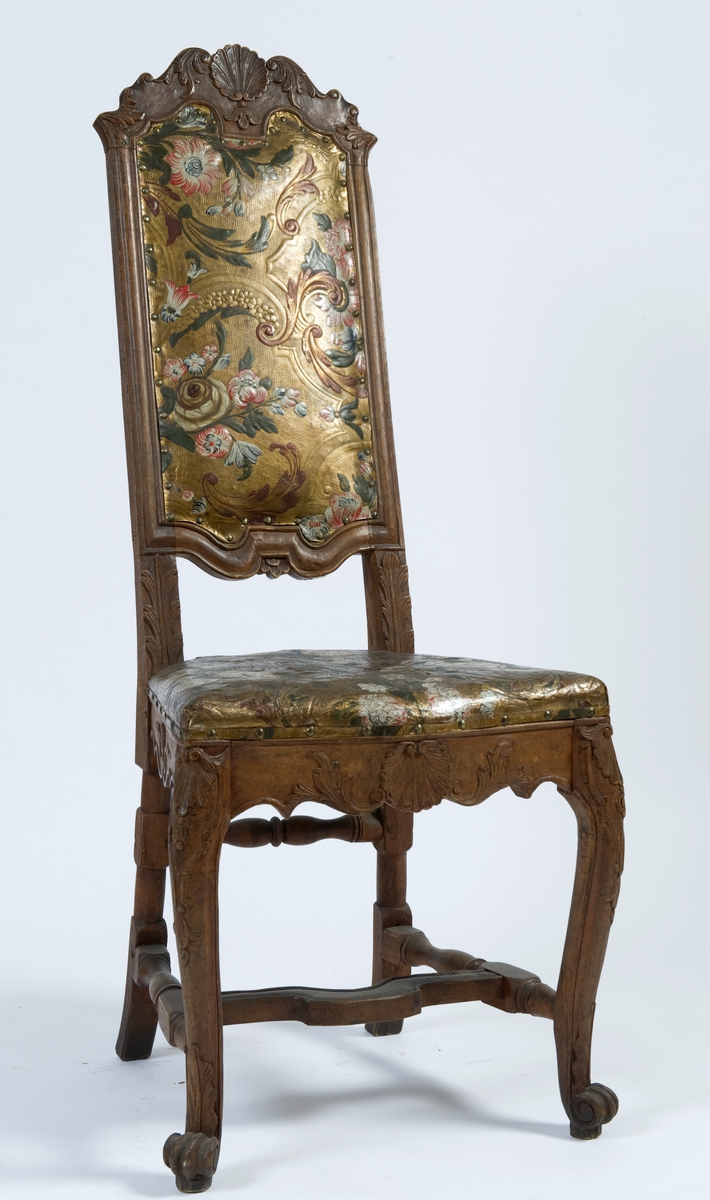 Regence-stol med ornamentikk i tre- og gyldenlærsarbeide som knytter den til rokokko-perioden.