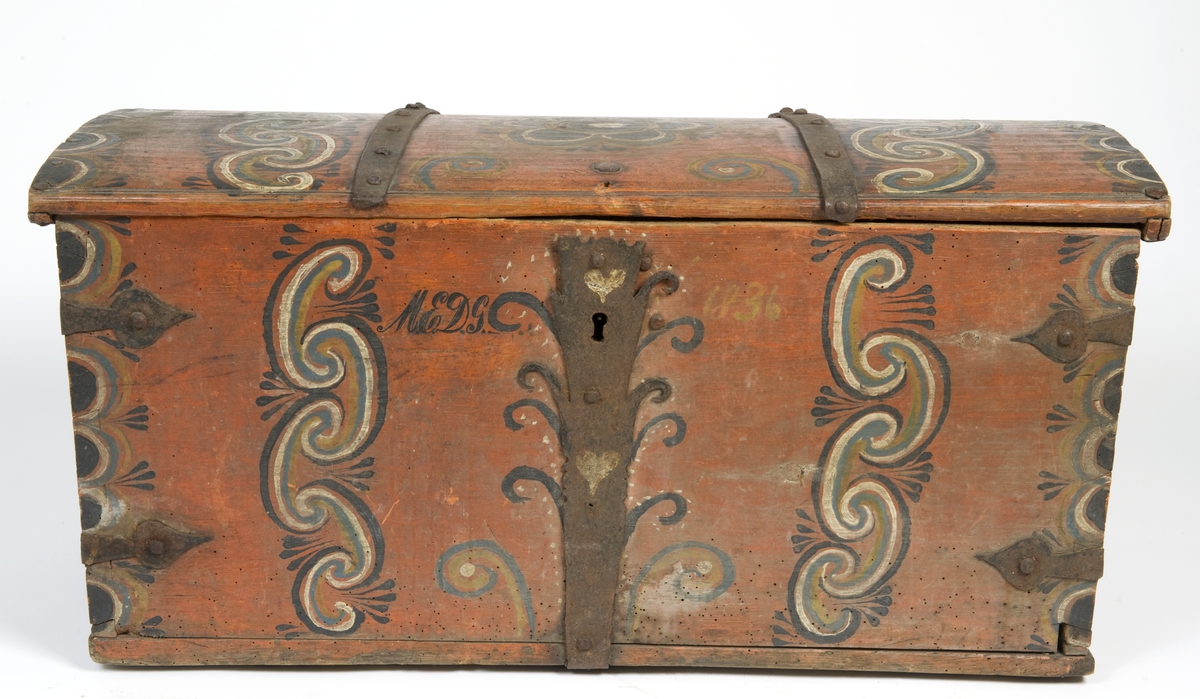 Kiste med svakt buet lokk. Malt dekor på alle sider og jernbeslag.