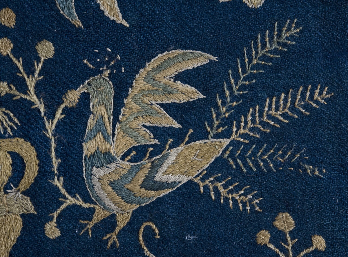 Mørkblå putetrekk med brodert dekor i ull.