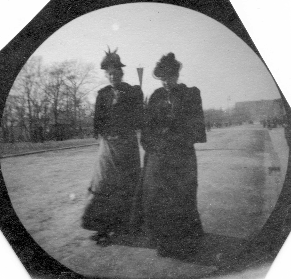 To damer spaserer på Karl Johans gate, Oslo, med ryggen til Slottet. Fra venstre: Ingeborg Dybwad, gift Lind, og Magnella Arentz.