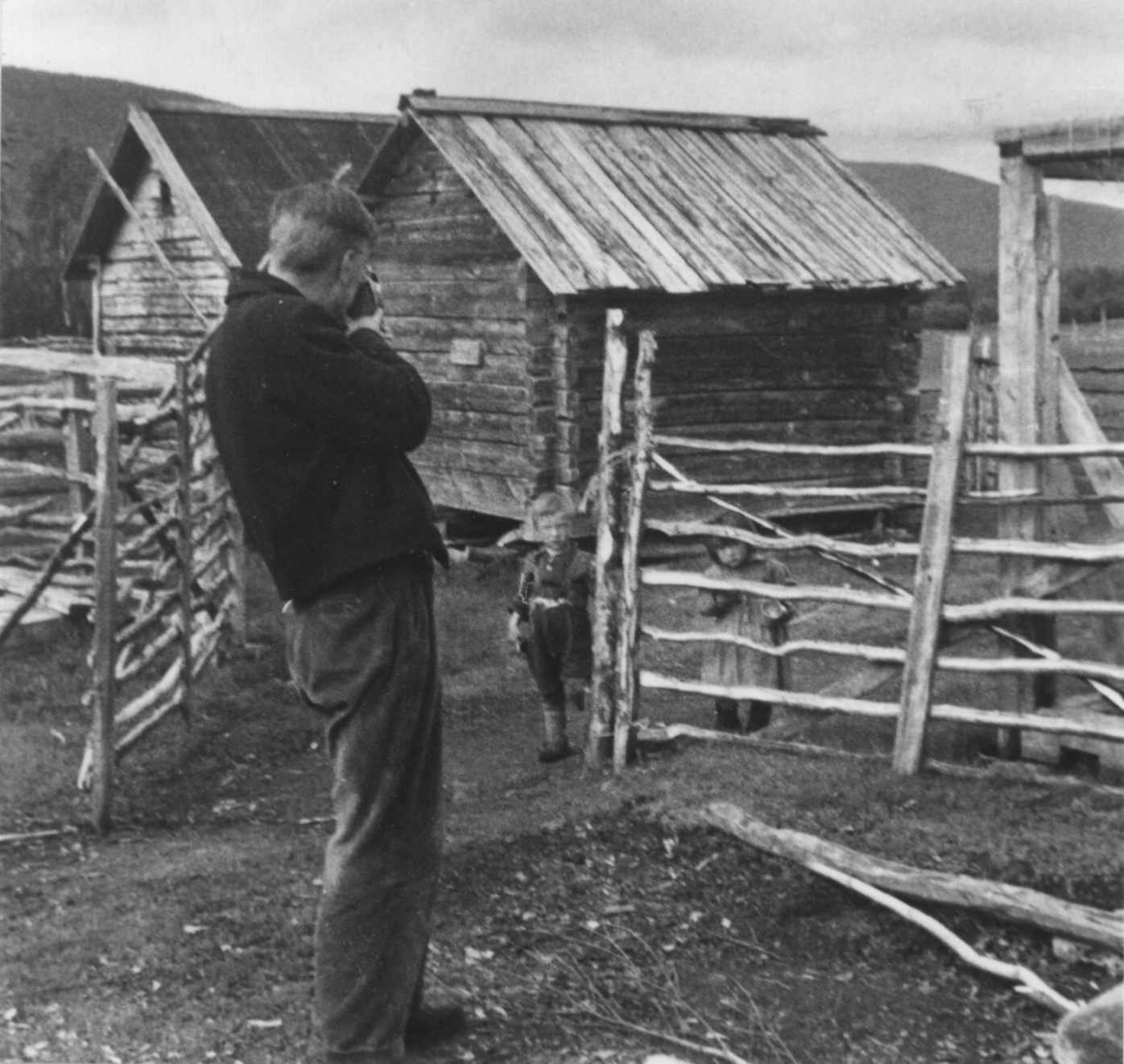 En mann fotografer stabbur og to barn. Port 1952.
