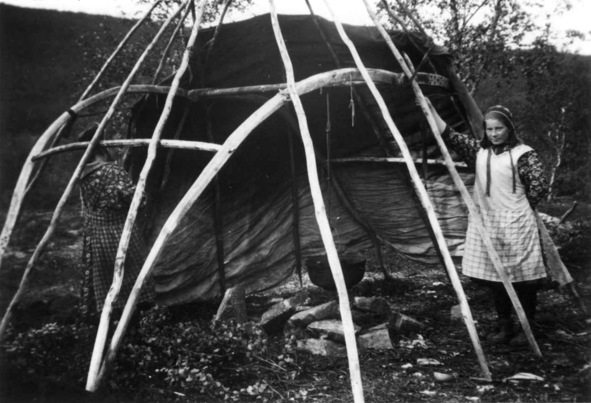 Demonstrasjon av oppsetting av telt, reisverket er satt opp og den en teltduken er lagt på. En kvinne står ved siden av. Sirma 1933.