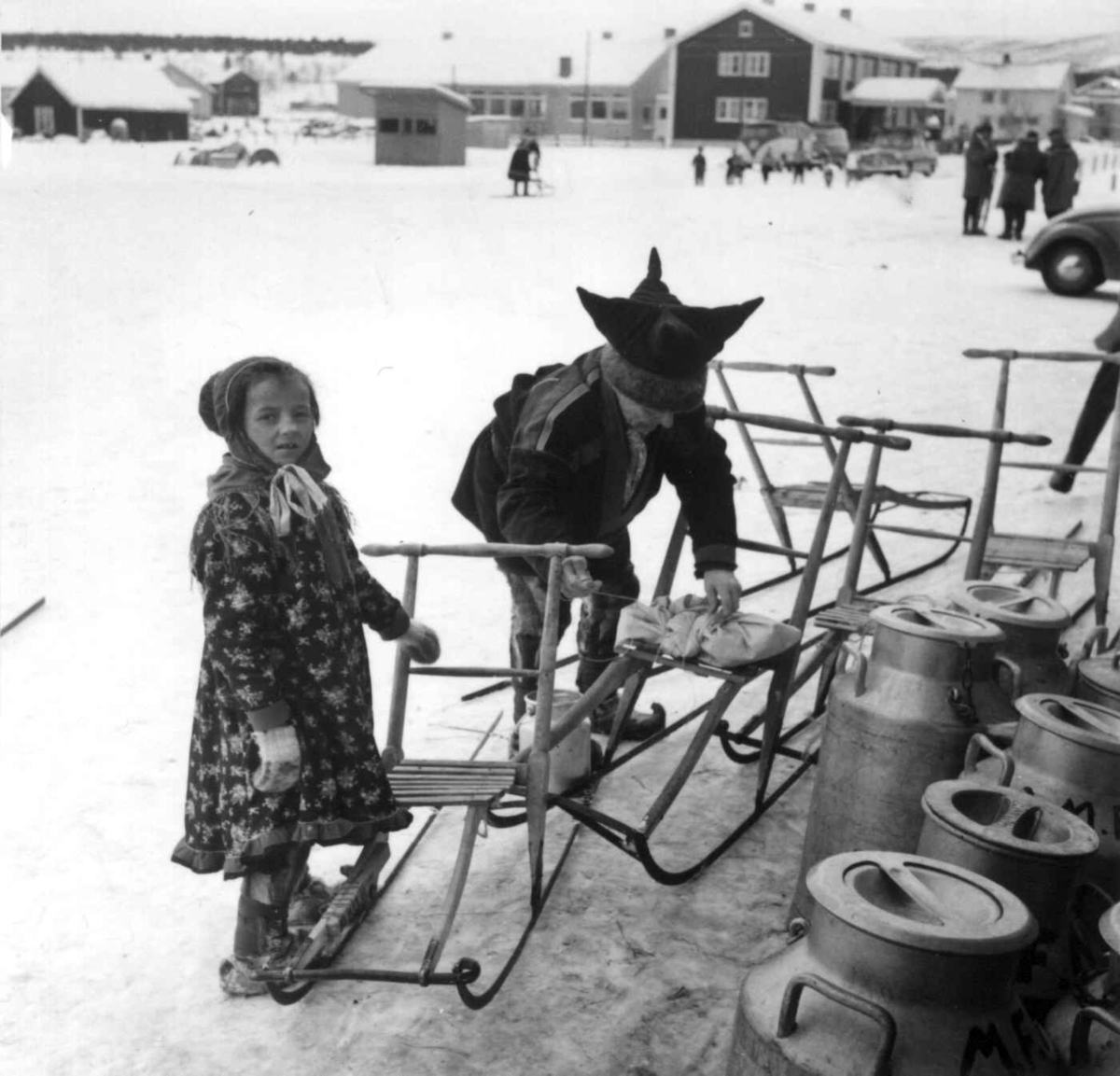 Barn med spark utenfor Samvirkelaget, melkespann i forgrunnen. Karasjok 1958.