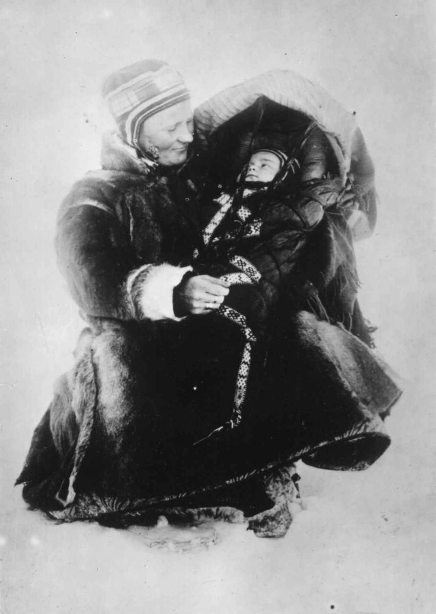 Kvinne med et barn i komse, Marit Banne med datteren Inga, Sør-Varanger, Finnmark, antatt tatt vinteren 1897.